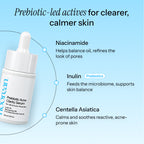 A promotional graphic for a skincare serum on a light blue background. The main subject is a white bottle labeled 'Noorean Prebiotic Acne Clarity Serum' with a dropper cap.